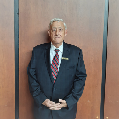 Older gentleman wearing a black suit and striped tie.