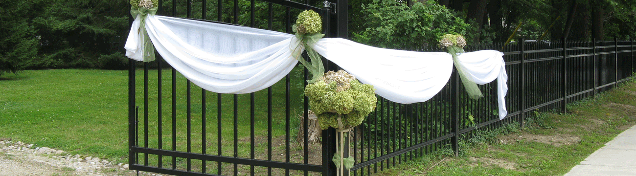 Gates decorated with white cloth and flower bouquets
