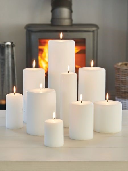 Nine white lit candles in a bunch, sitting on a counter.