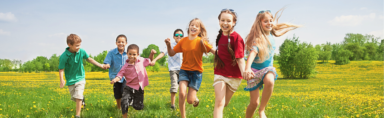 A group of kids running in a field during the summer.